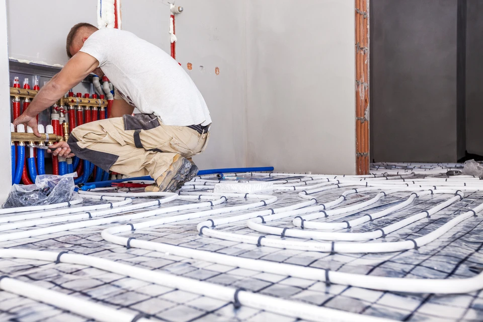 Chantier intérieur de construction avec technicien installant un système de chauffage au sol