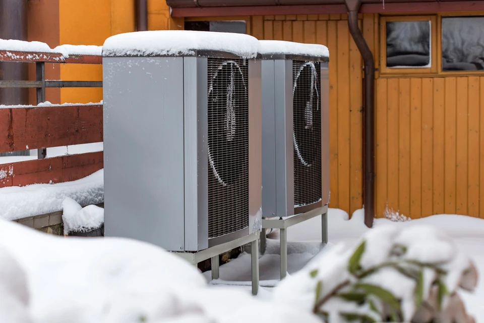 Scène extérieure hivernale avec unités de pompe à chaleur air-air installées sur supports métalliques dans jardin enneigé