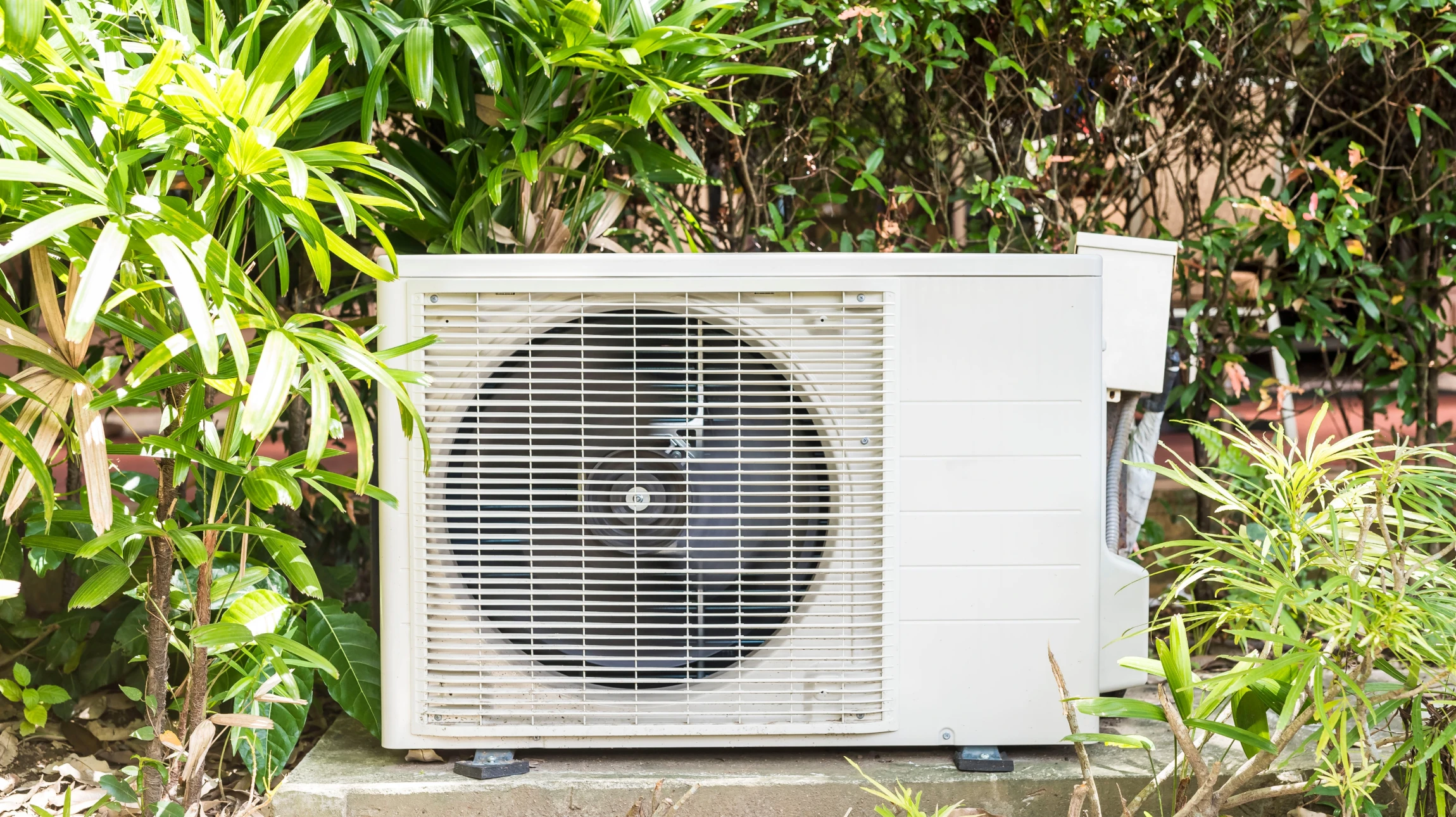 Extérieur résidentiel avec deux pompes à chaleur air-eau installées sur lit de gravier, bordure d'herbe visible