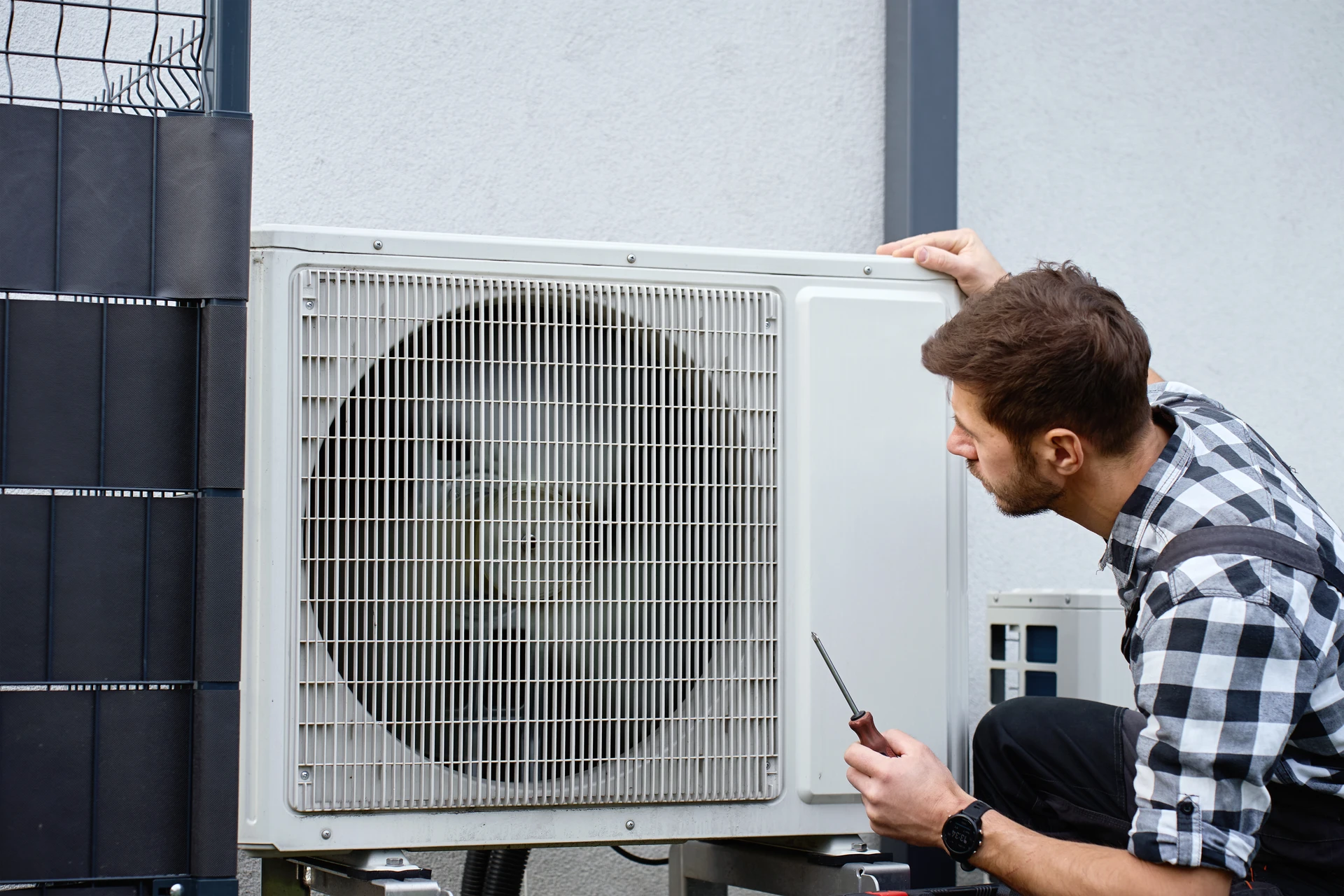 Intérieur moderne avec système de climatisation split composé d'une unité extérieure compacte blanche avec grille de ventilation et d'une unité intérieure murale avec affichage digital